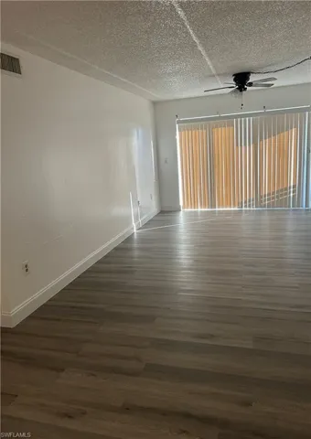 Unfurnished room featuring a ceiling fan and dark wood finished floors