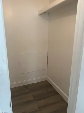Walk in closet with dark wood-style floors