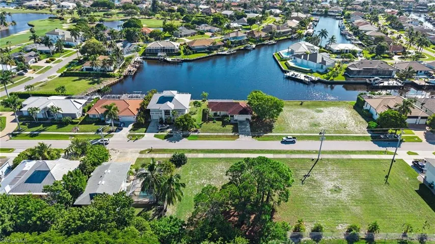Aerial perspective featuring a waterfront parcel with direct canal access, mature trees, and established residential landscaping