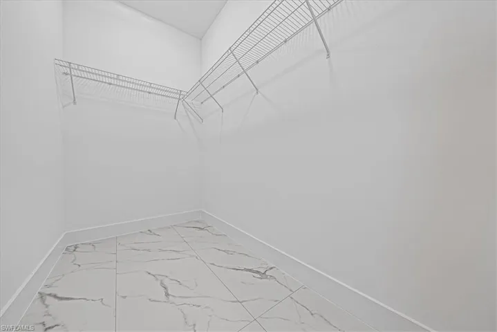 Walk in closet with light marble finish flooring