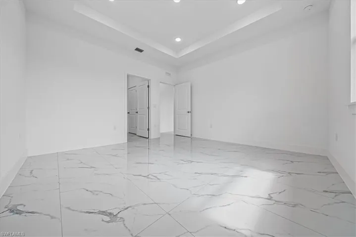 Unfurnished bedroom featuring a tray ceiling and recessed lighting