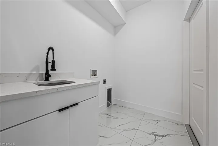 Laundry area featuring light marble finish floors, hookup for a washing machine, hookup for an electric dryer, and cabinet space