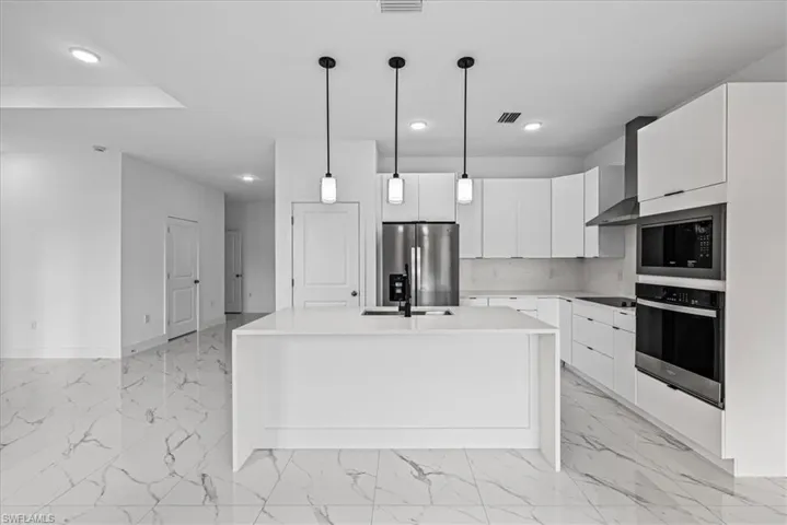 Kitchen featuring stainless steel appliances, white cabinets, modern cabinets, and light stone countertops