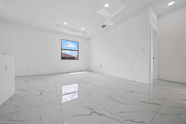Spare room with light marble finish floors, recessed lighting, and a raised ceiling