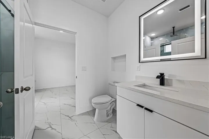 Bathroom with light marble finish flooring, vanity, and a shower