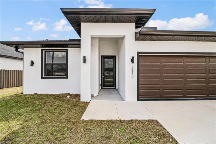 View of front of property featuring an attached garage, stucco siding, and driveway