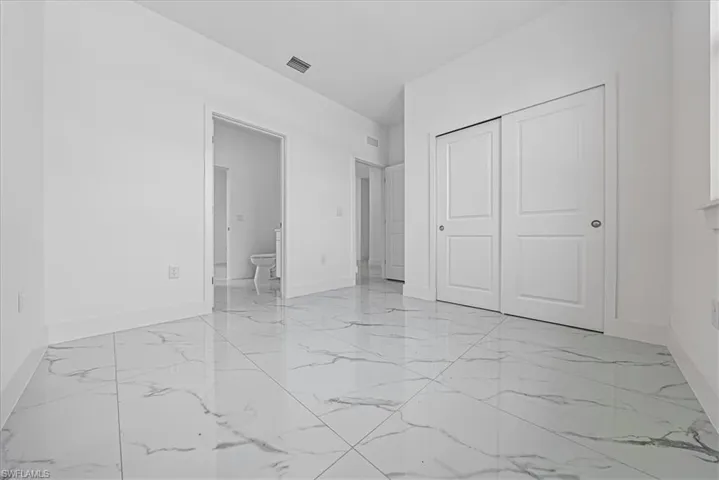 Unfurnished bedroom featuring a closet and light marble finish floors