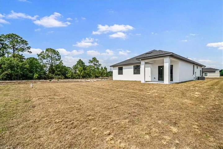 Back of house with a patio area, stucco siding, and a yard