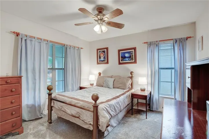 Carpeted bedroom featuring multiple windows and ceiling fan
