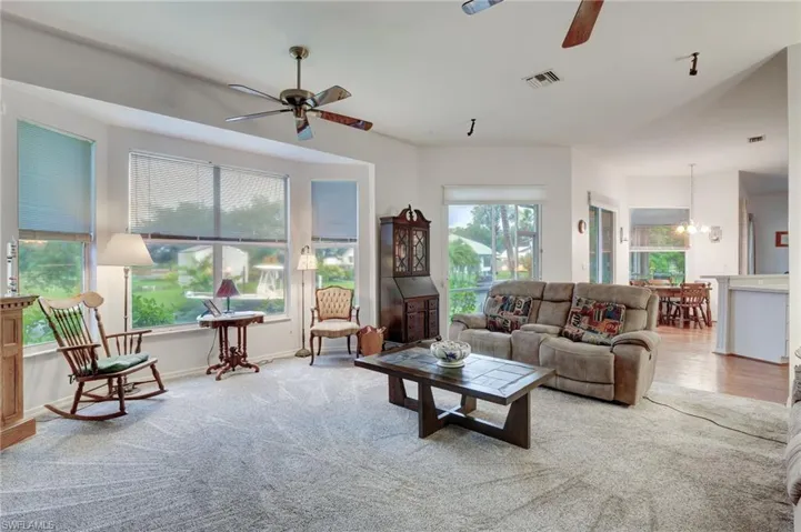 Carpeted living room with ceiling fan with notable chandelier