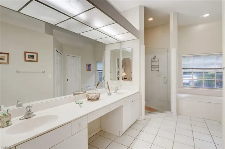 Bathroom featuring double sink vanity, tile floors, and plus walk in shower