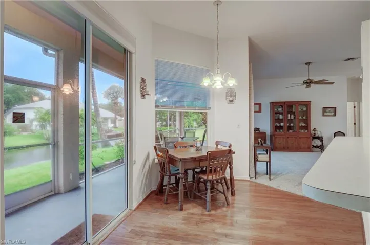 Carpeted dining room with a wealth of natural light and ceiling fan with notable chandelier