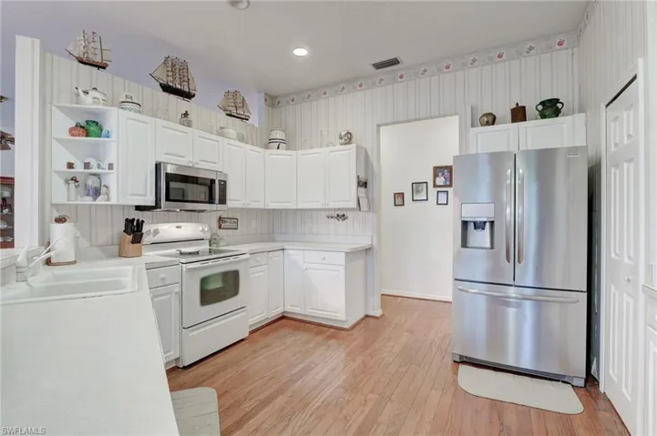 Kitchen featuring sink, backsplash, light wood-type flooring, and stainless steel appliances