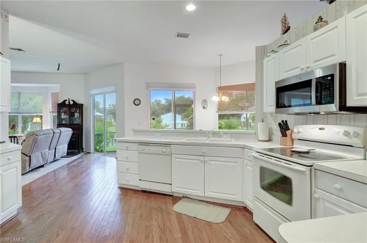 Kitchen with white appliances, light hardwood / wood-style floors, and a healthy amount of sunlight