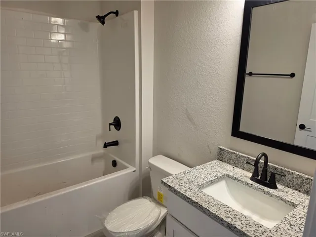 Bathroom featuring a vanity with a stone-composite countertop, white rectangular undermount sink, matte black faucet, and matching black hardware