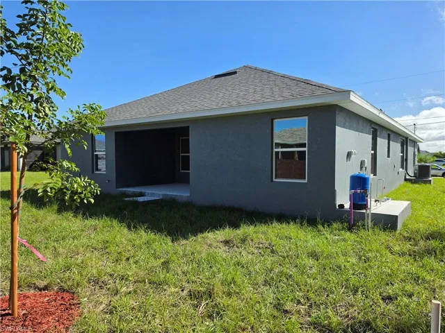 Stucco exterior featuring a covered patio, hipped roof, multi-pane windows, and a water filtration system