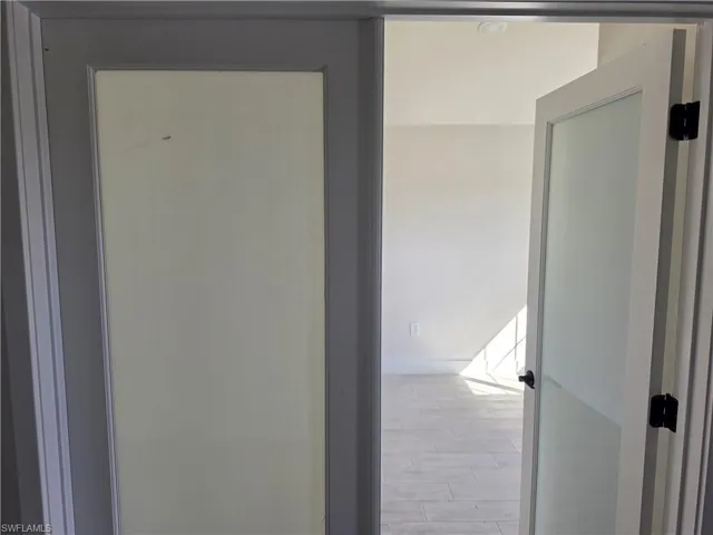 Shaker-style door with frosted glass panel, contrasting gray door frame, and tile flooring