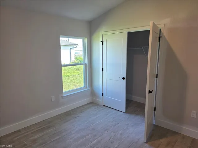 Room featuring wood-finish tile flooring, a window, and a white two-panel closet door with matte black hardware