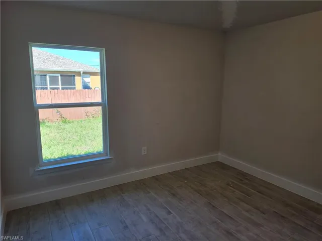Room featuring neutral wall paint, wood-finish flooring, and a single-hung window with a sill