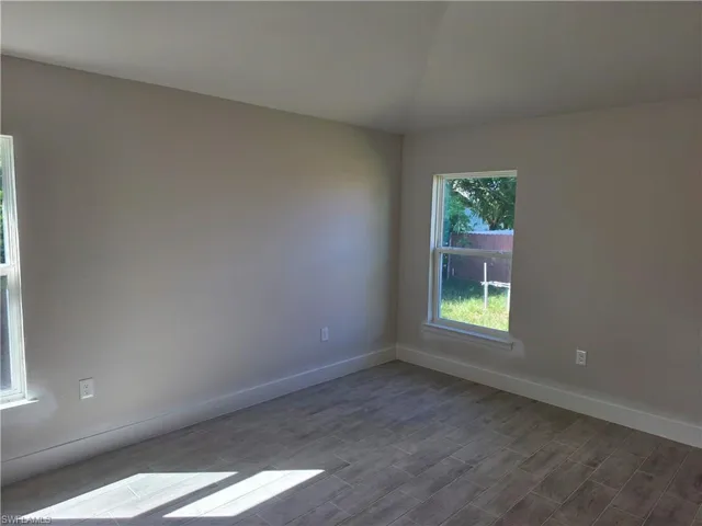 Neutral interior space featuring wood-finish tile flooring, vaulted ceiling, and dual double-hung windows