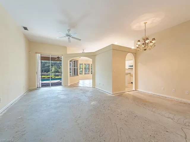 Unfurnished living room featuring ceiling fan with notable chandelier