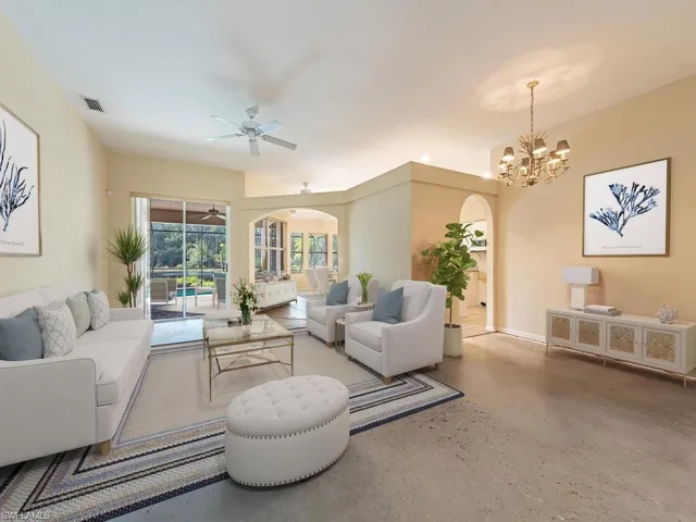 Living room featuring concrete floors and ceiling fan with notable chandelier