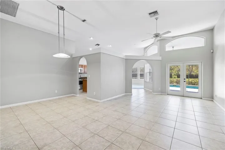 Unfurnished living room featuring a high ceiling, ceiling fan, french doors, and light tile floors