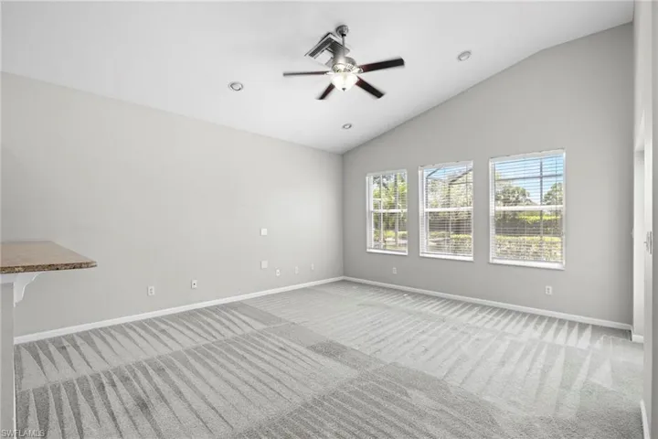 Unfurnished room with vaulted ceiling, ceiling fan, and carpet floors