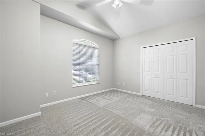 Unfurnished bedroom featuring a closet, ceiling fan, carpet floors, and lofted ceiling