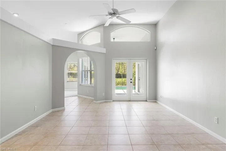Tiled empty room featuring high vaulted ceiling, ceiling fan, and french doors