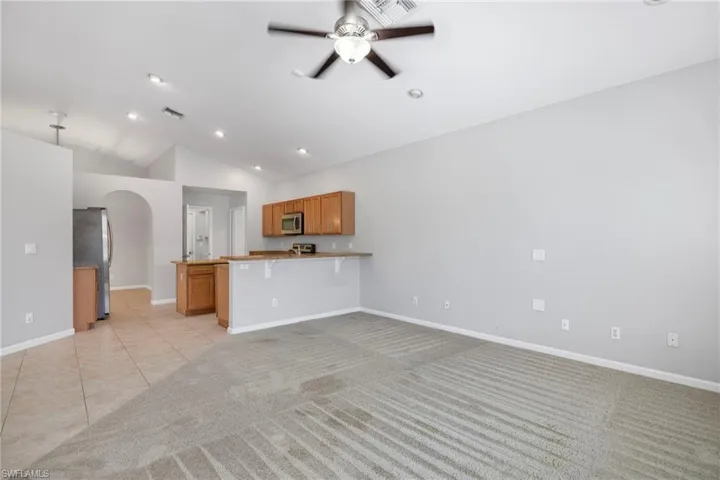 Unfurnished living room with high vaulted ceiling, ceiling fan, and light tile floors