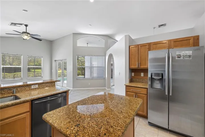 Kitchen featuring appliances with stainless steel finishes, a center island, and light stone countertops