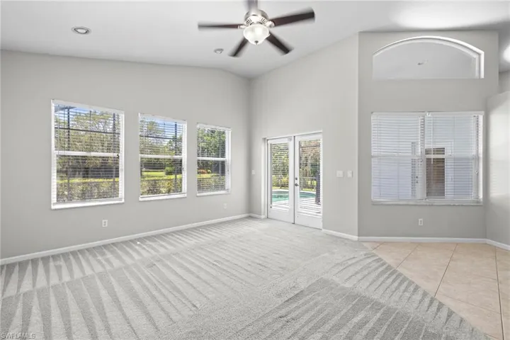 Empty room featuring light colored carpet, ceiling fan, and lofted ceiling
