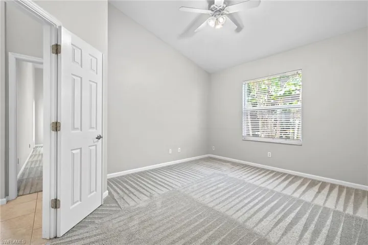 Tiled spare room featuring ceiling fan and lofted ceiling