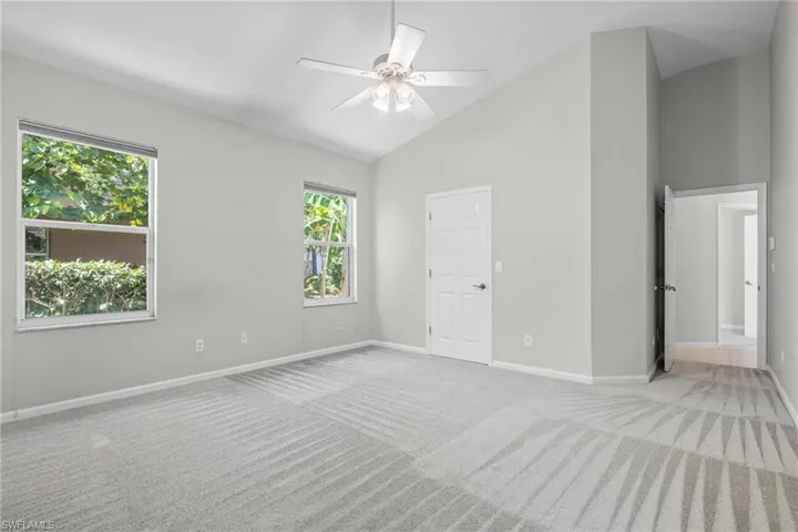 Carpeted empty room featuring high vaulted ceiling and ceiling fan
