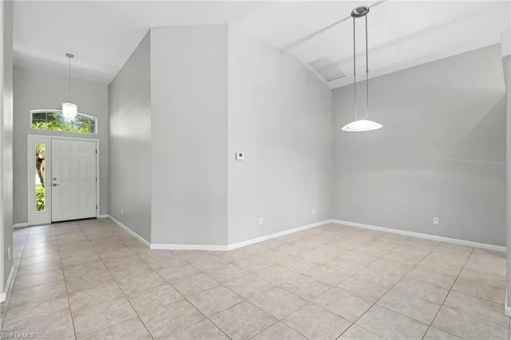 Entryway with high vaulted ceiling and light tile floors