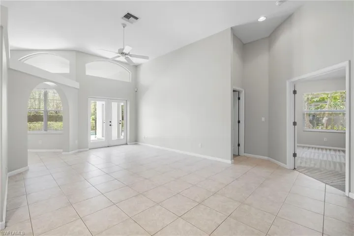 Tiled spare room with high vaulted ceiling, ceiling fan, and french doors