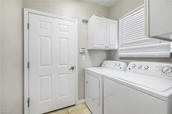 Laundry room featuring washer and dryer, cabinets, and light tile floors