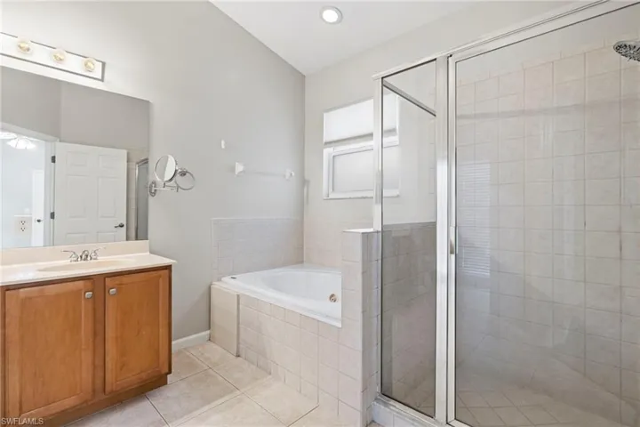 Bathroom featuring tile flooring, large vanity, and separate shower and tub