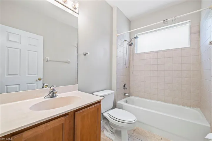 Full bathroom with tiled shower / bath, vanity, toilet, and tile floors