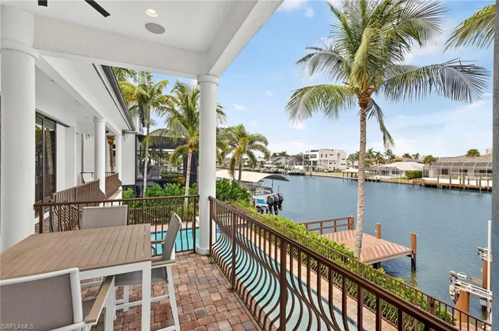 Balcony with a dock, a water view, a ceiling fan, and boat lift