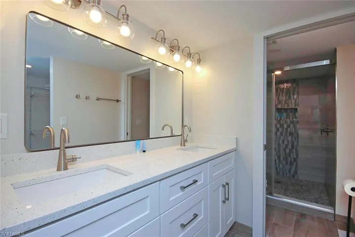 Full bath with a sink, wood finished floors, a stall shower, and double vanity