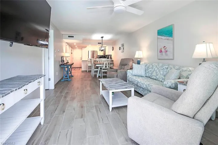 Living area with a ceiling fan, visible vents, and wood finish floors