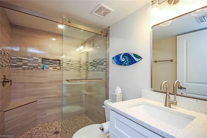 Bathroom with visible vents, a walk in shower, toilet, and vanity