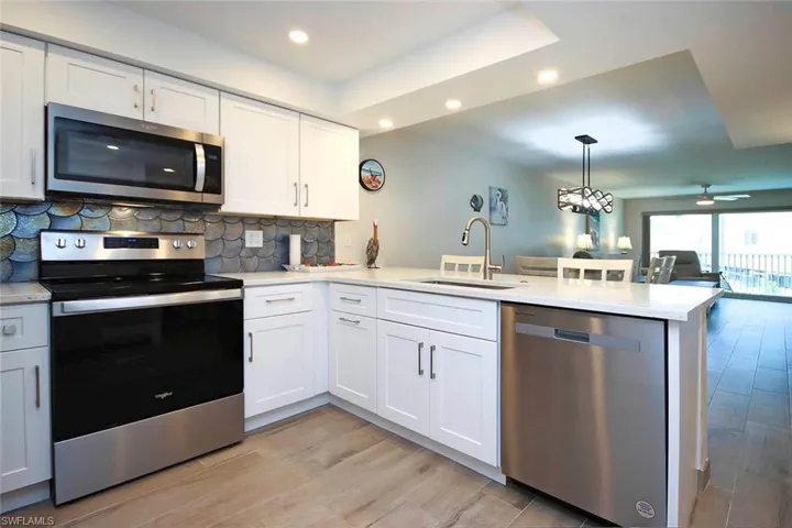 Kitchen featuring a sink, tasteful backsplash, stainless steel appliances, a peninsula, and light countertops