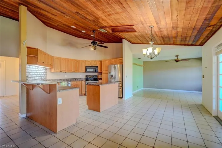 Kitchen with a center island, wood ceiling, black appliances, and decorative light fixtures