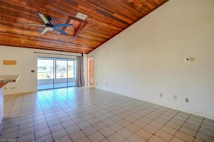 Spare room with lofted ceiling, ceiling fan, wooden ceiling, and light tile patterned floors