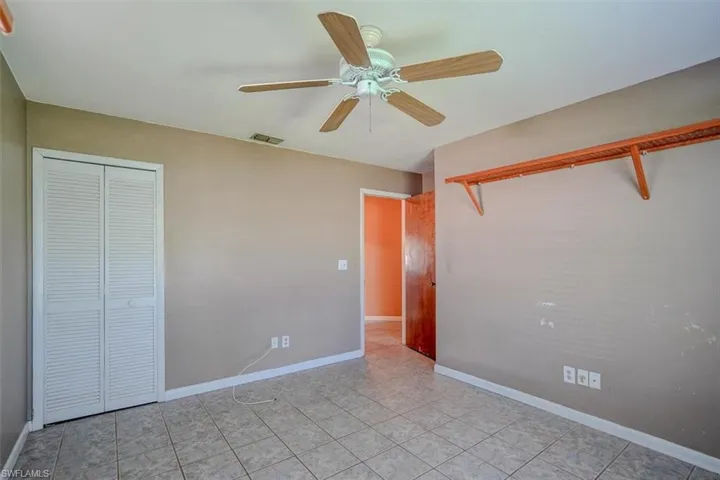 Unfurnished bedroom with a closet, light tile patterned floors, and ceiling fan