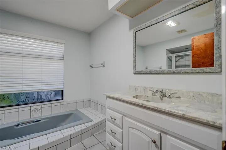 Spare Bathroom with tile patterned flooring, separate shower and tub, and vanity