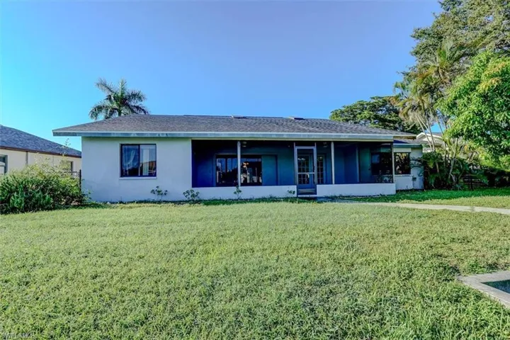 View of front facade with a front lawn and a sunroom